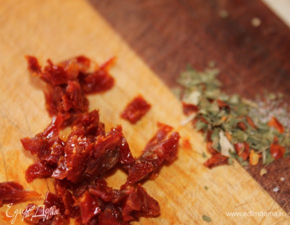 Вяленые помидоры нарезать на тонкие полоски, а затем на мелкие кубики. Смешать лук помидоры и травы.