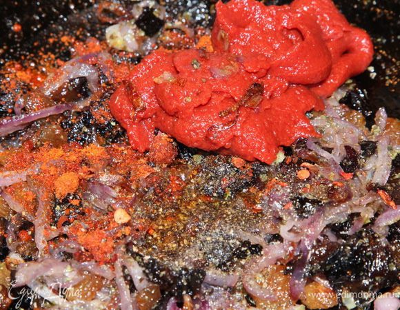 Добавить томатную пасту, паприку и перец. Чуть подсолить и подлить воды. Перемешать и тушить на среднем огне до испарения жидкости, около 10 минут.