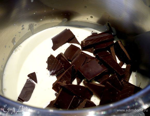 Достаем тарт из духовки. Температуру в духовке сокращаем до 120 градусов. Сливки доводим на огне до первых пузырьков. Снимаем с огня и сразу вмешиваем деревянной лопаточкой поломанный на кусочки шоколад. 