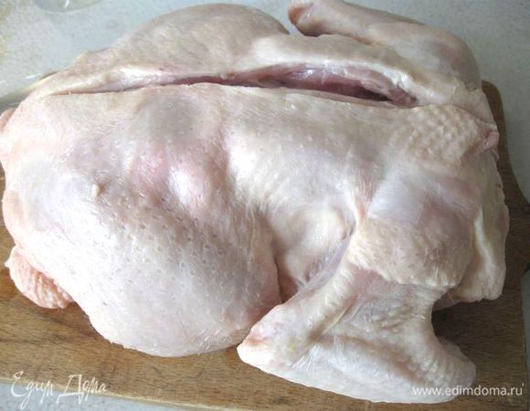 Положить курицу на доску грудкой вниз, надрезать по хребту.  