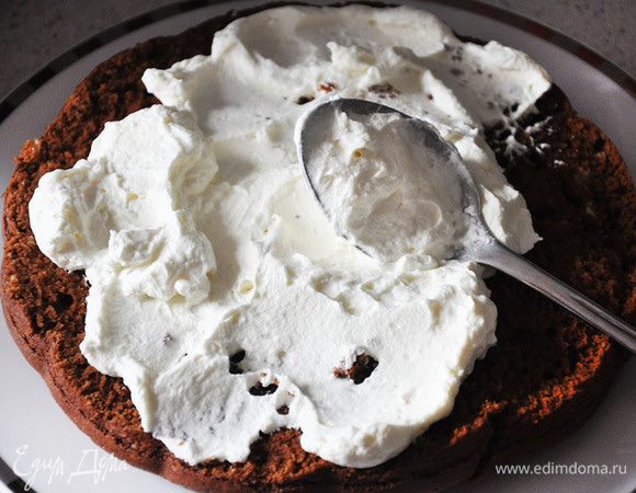 Приготовить крем. Взбить сливки до густоты, добавить пудру. Немного отложить в кондитерский шприц для украшения. Остальное выложить на нижний корж. Сверху накрыть вторым коржом. 