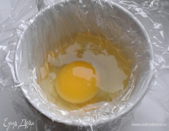 Смажьте пленку растительным маслом, затем осторожно разбейте яйцо и вылейте его в кружку. 