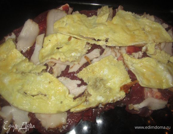 Яичницу остудить, порезать на кусочки и ровным следующим слоем выложить на шпик.