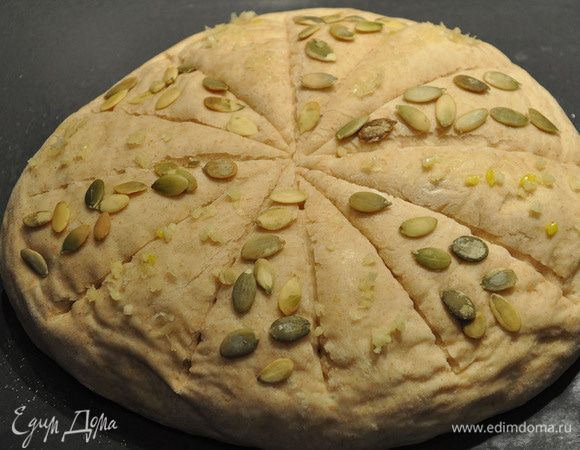 Выдавить на тесто чеснок через чеснокодавку и посыпать семечками.