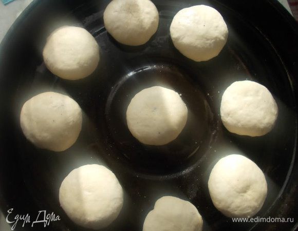 Тесто разделить на 9-10 булочек. Хорошо каждую замесить,как-бы заворачивая тесто во внутрь, выложить на смазанный маслом противень. 