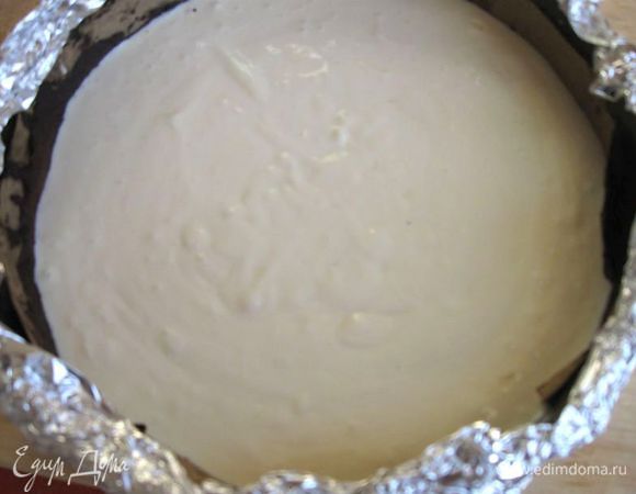 Равномерно положить массу на выпеченную основу .Обернуть форму снаружи фольгой таким образом, чтобы в форму не попала вода из водяной бани (кусок фольги должен быть цельным). Поставить форму с содержимым в термостойкую посуду большего размера, заполненную кипятком. Поставить на нижнюю полку духовки, разогретой до 180 градусов на 35 минут. Выключить газ.  Оставить на 45 минут в духовке с приоткрытой дверцей.
