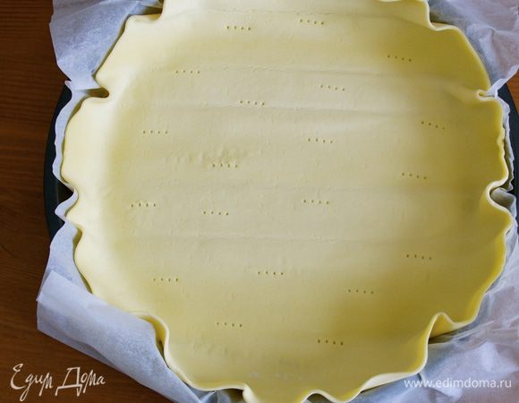 Слоеное тесто выложить вместе с пекарской бумагой в форму для выпечки. Оставить свободный край. Наколоть тесто вилкой. 