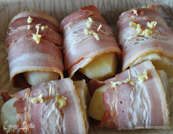 Закрепить бекон зубочистками. Уложить в форму. Полить картофель маслом. Выдавить сверху чеснок. Выпекать при 180 гр около 20 минут.