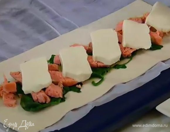 На тесто в линию по центру, оставив края пустыми, выложить шпинат, затем рыбу и половинки вяленых помидоров, а сверху моцареллу.