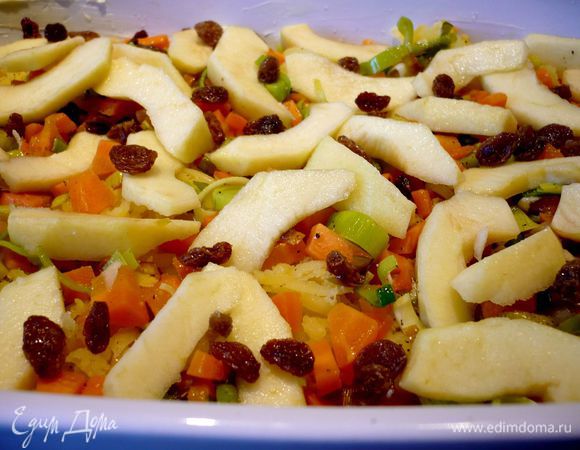 Форму смазываем маслом. Выкладываем натертый на крупной терке картофель. Сверху распределяем овощи, затем ломтики яблок и изюм.