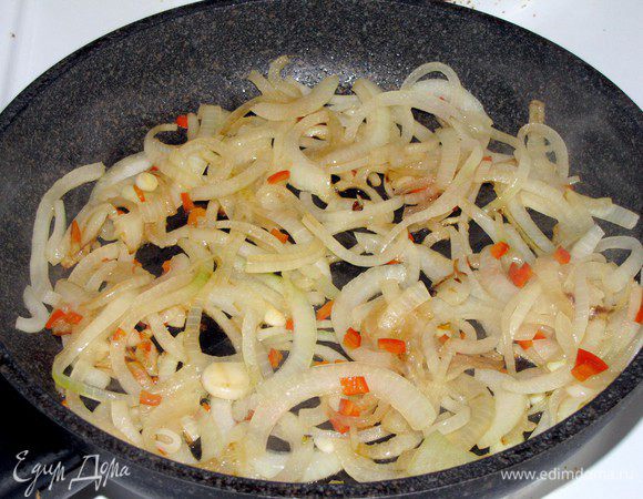 Приготовить соус. Крупную луковицу очистить и нарезать тонкими полукольцами. Оставшиеся перчики чили измельчить. Обжарить лук и перцы в 1 ст. л. разогретого кукурузного масла ( у меня оливковое), 5 минут.