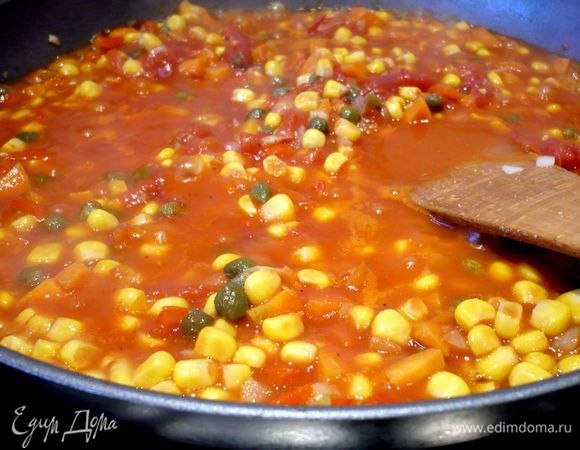 Духовку разогреем до 180 градусов. Почистим и порежем лук и морковь. Перец порежем мелким кубиком. Обжарим овощи в оливковом масле до золотистого цвета. Добавим кукурузу и томаты с соком, разомнем помидоры вилкой, добавим каперсы, сахар, посолим и поперчим и потушим на медленном огне еще несколько минут. Добавим базилик, перемешаем. 