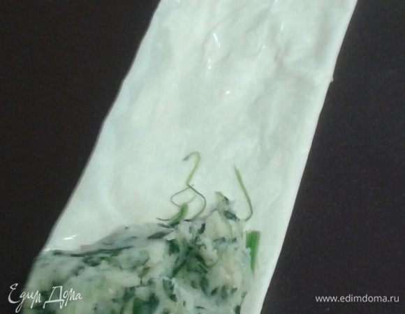 Положите на угол полоски начинку.