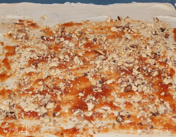 Орехи размяла при помощи скалки и половину выложила равномерно на повидло.