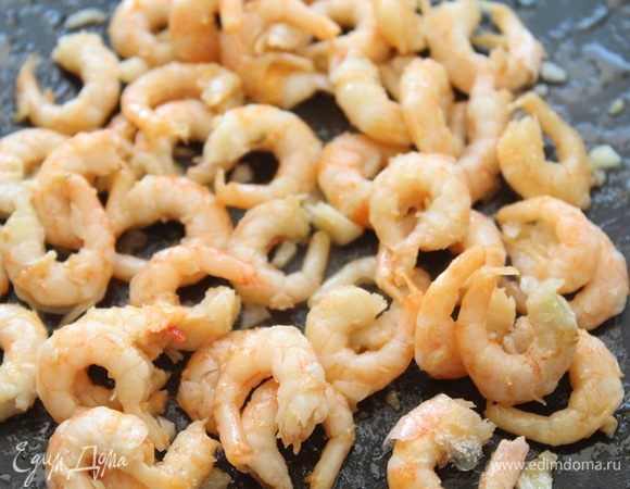 Если креветки замороженные, обдать  их горячей водой, выложить на сковороду вместе с оливковым маслом и чесноком. Обжарить до золотистого цвета.