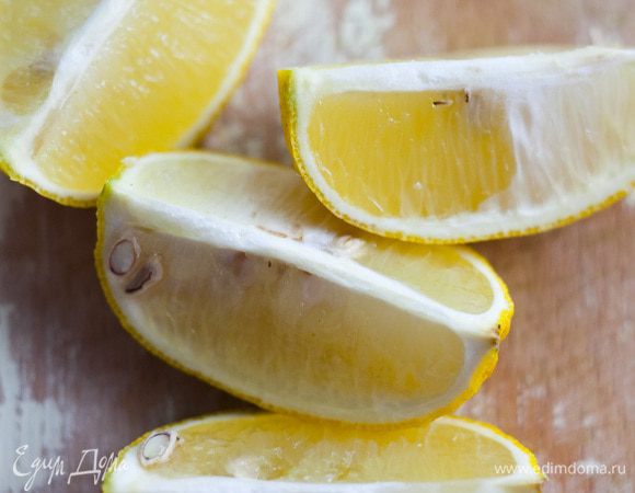 Лимон разрезать на 4 части и вложить внутрь курицы. Противень смазать частью растительного масла и уложить в него курицу.