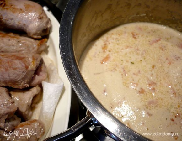 Вливаем сливки и добавляем помидоры, перемешиваем, с рулетиков снимаем листики шалфея, извлекая зубочистки, и выкладываем рулетики в соус, тушим на небольшом огне в течение 10 минут. 