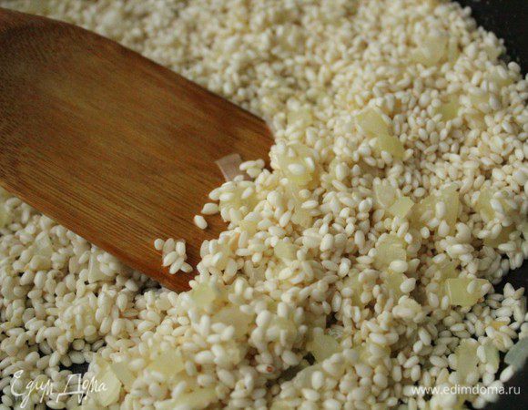 Добавить к луку рис и, постоянно помешивая, дать рису стать полупрозрачным.