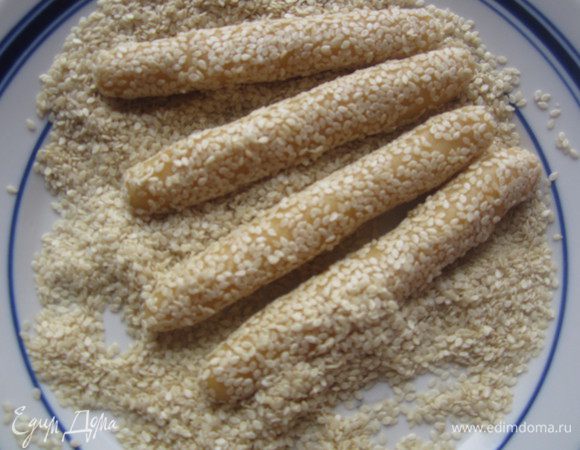 Самый приятный момент. Обвалять палочки в семенах кунжута (можно также попробовать рубленные тыквенные семечки или семя подсолнечника- экспериментируйте!) Выложить эту красоту на противень, посыпанный мукой и выпекать 15 минут при 180 С.