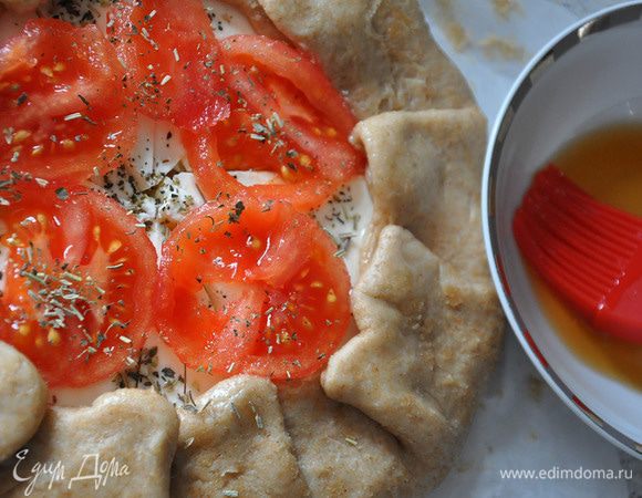 Выложить очищенные от кожуры кружки помидора. Полить маслом и посыпать травами. Смазать тесто чайной заваркой (для оттенка).