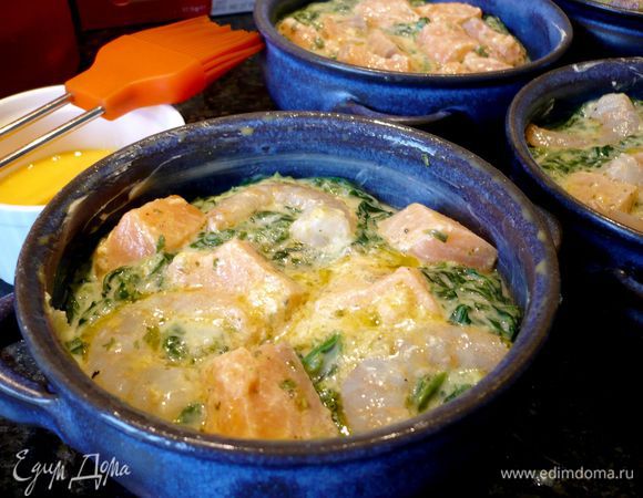 Духовку разогреваем до 200 градусов. Желток смешиваем с 2 ст.л. холодной воды. Формы для выпечки (у меня диаметром примерно 12 см каждая, всего получилось 5 формочек) смазываем снаружи и изнутри сливочным маслом. Ободки форм смазываем желтком. Выкладываем сначала часть рыбки с креветками на дно, затем часть шпинатно-сливочного  соуса и снова рыбку с креветками. 