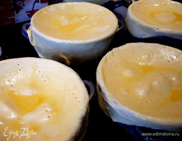 Тесто раскатываем на присыпанной мукой поверхности (помните, что вам понадобится  только половина теста) и вырезаем круги, на пару сантиметров больше, чем диаметр формы.  Протыкаем круги часто вилочкой и выкладываем крышечки из теста на формы для запекания. Края теста прижимаем к формам. Смазываем верхушки желтком и ставим в духовку на 25 минут.