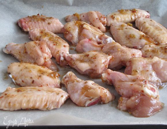 Обмазать крылышки получившейся глазурью и выложить на противень, застеленный пекарской бумагой.