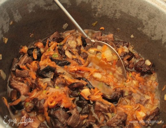 Грибы откинуть на дуршлаг(воду,в которой они вымачивались,процедить,отставить). Добавить грибы в казан к луку и моркови,помешивая,обжаривать 5 минут.