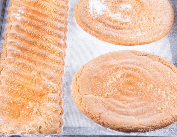 осыпать бисквиты сахарной пудрой и выпекать в предварительно разогретой духовке. Я выпекала при 180 ° С в течение 10 минут. Остудить на противне, затем снять и разрезать полосу на 2 части вдоль, что получились полоски шириной 5 см и длинной 40 см.