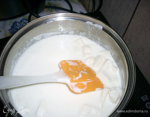 Приступаем к приготовлению крема. В кастрюльку со сметаной добавляем нарезанные небольшими кусочками плавленные сырки. Ставим кастрюльку на средний огонь. Помешиваем содержимое лопаткой и ждем, пока сырки полностью растопятся  в сметане.