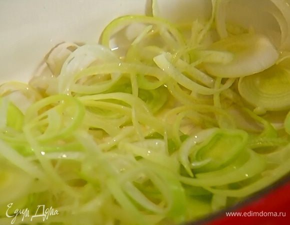 В тяжелой кастрюле разогреть оливковое масло и обжарить лук-порей до легкого золотистого цвета.