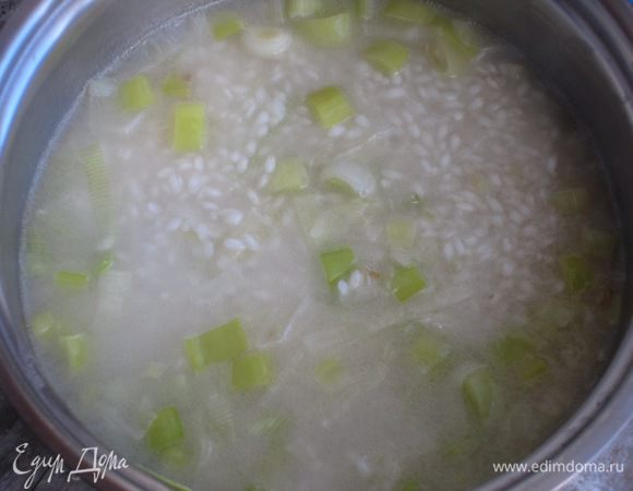 Влить вино и готовить,постоянно помешивая,пока вино не испарится.Добавить половник горячего бульона.По мере того,как рис будет впитывать жидкость,подливать небольшое количества бульона.
