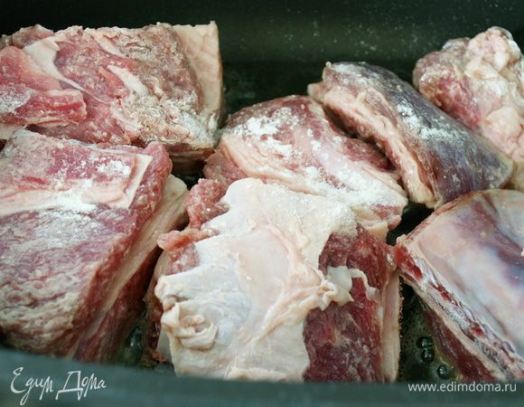 В большой сковороде (казанке) с тяжелым дном (которую можно затем поставить в духовку) разогреть оливковое масло. Ребрышки слегка обвалять в муке и положить обжариваться в казанок. Обжарить со всех сторон до золотистой корочки.