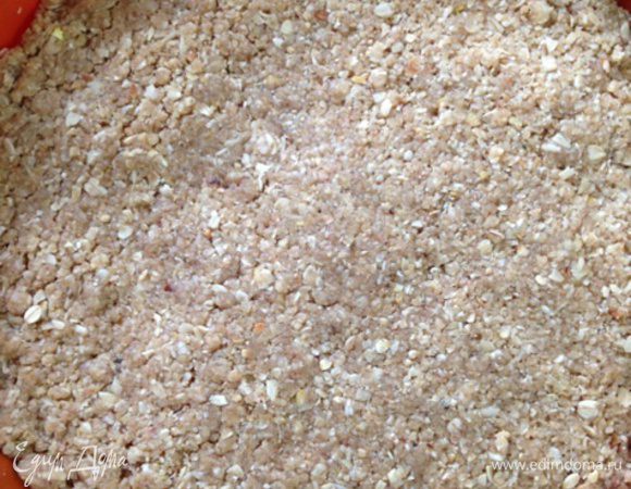 Теперь берем форму (у меня силиконовая диаметром 18 см) и выкладываем половину нашей крошки, слегка утрамбовывая ее руками.