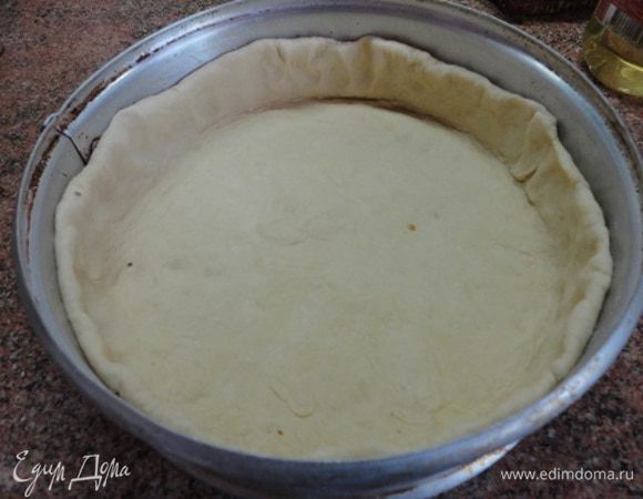 Тесто раскатать в круглый пласт и выложить им смазанную жиром разъемную форму диаметром около 24 см, сделав бортики высотой 3-4 см. Дать постоять минут 15 и затем выложить начинку.