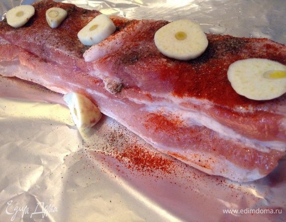 Натереть солью, перцем. Нарезать чеснок и разложить на кусок грудинки.