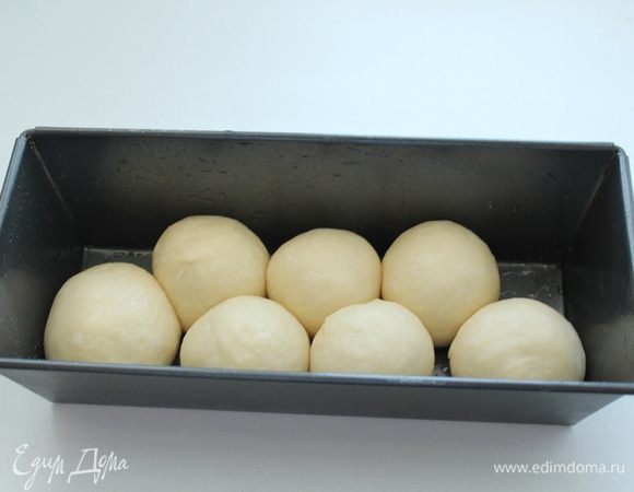 Когда тесто увеличится вдвое, обмять его и разделить на 16-20 шариков.
Смазанными растительным маслом руками,выложить в смазанную маслом форму для выпечки половину шариков.
