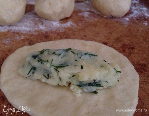 Разделить охлаждённое тесто на шарики одинакового размера. Расплющить каждый шарик в лепёшку и положить в середину начинку.