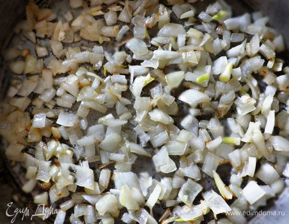 В сковороде нагреть растительное масла.  Дольку чеснока раздавить тыльной стороной ножа и обжарить в сковороде на растительном масле. Затем чеснок вынуть. Добавить мелко нарезанный лук и немного подрумянить. 