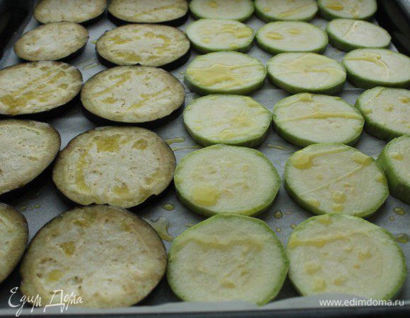 Противень застелить бумагой для выпечки, выложить колечки кабачка и баклажана, сбрызгнуть маслом и посолить.