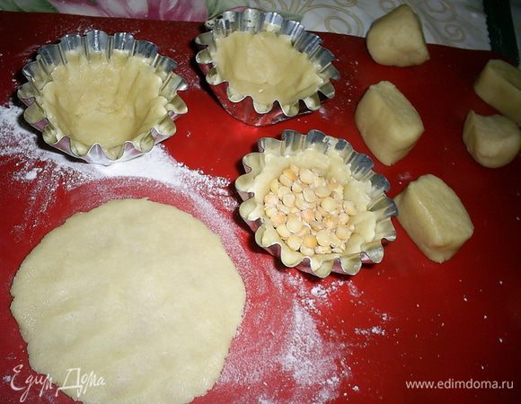 Каждую часть раскатываем в лепешку и переносим в формочку для выпечки кексиков, формочки дополнительно жиром смазывать не надо. Затем желательно положить сверху на заготовку кружок пергамента, диаметр которого равен диаметру раскатываемых лепешек, и только затем заполнить формочки сухим горохом или фасолью. Честно говоря, я поленилась, все получилось замечательно, только нижний слой гороха немного ко дну корзиночки прилип))) Выпекаем корзиночки при 180 градусах 15 минут, затем вынимаем наполнитель и даем еще 5 минут подрумяниться.