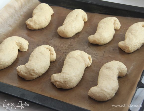 Из каждой части сформировать жгутик, скрутить жгутик в виде латинской S, булочки уложить на противень с антипригарным ковриком.