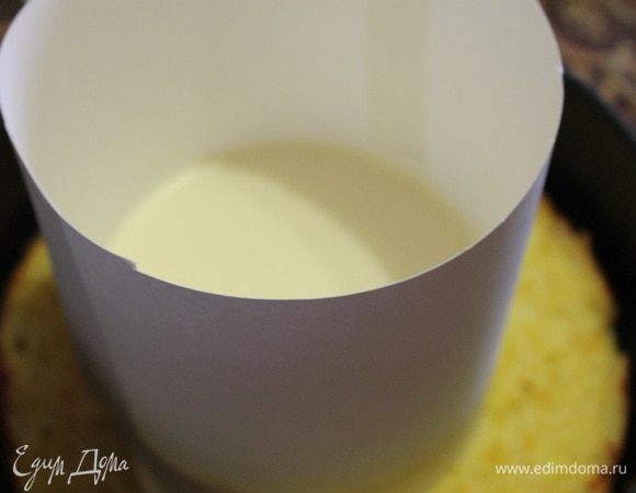 Теперь к творогу с цедрой добавляем понемногу сливки и взбиваем все вместе. Далее добавляем распущенный и остывший желатин постепенно, и опять взбиваем. Из бумаги для черчения я соорудила кольцо меньшего диаметра, поставила его на бисквит и вылила апельсиновый мусс. Потом осторожно переносим нашу конструкцию в морозилку на 30 минут.