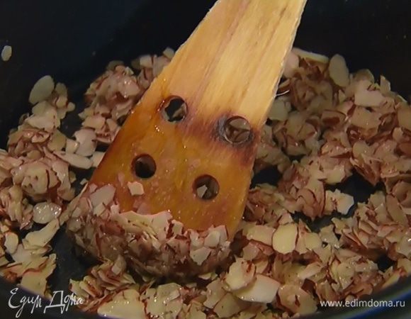 Приготовить нугу: хлопья миндаля подсушить в тяжелой кастрюле, добавить сахар и мед и прогреть, периодически помешивая.  