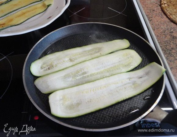 Цукини нарезать вдоль тонкими полосками. В рецепте предлагалось бланшировать их 3 минута, а затем готовые рулетики перед тушением обжаривать. Я сделала, по-моему, проще и удобнее. Хорошо бы на сковороде гриль поджарить слегка сбрызнутые маслом цукини, но у меня таковой нет, поэтому я использовала блинную сковороду с антипригарным покрытием. Правда, немного смазывала растительным маслом.