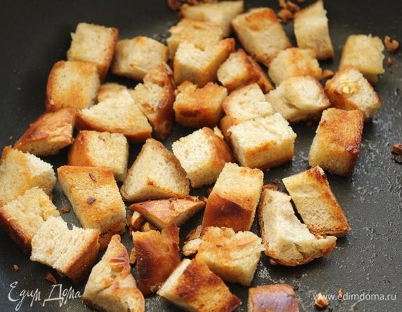 В сковородке разогреть 1-2 ст. л. оливкового масла, выдавить туда же дольку чеснока, порезать хлеб кубиками и обжарить.