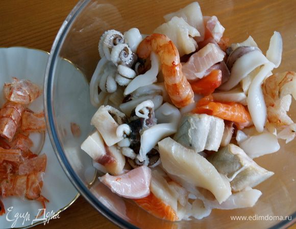 Подготовить рыбу и морепродукты. Как следует промыть. Кальмаров нарезать. Подготовить рыбное филе; очистить от костей и кожи, нарезать небольшими кусочками, креветочные хвосты очистить от панциря и удалить черную прожилку-пищевод. Сбрызнуть рыбу лимонным соком.  