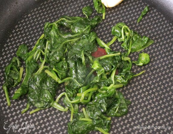 Готовый шпинат будет выглядеть вот так... Он сильно уменьшится в размере и потемнеет. Удалить чеснок и остудить шпинат.  