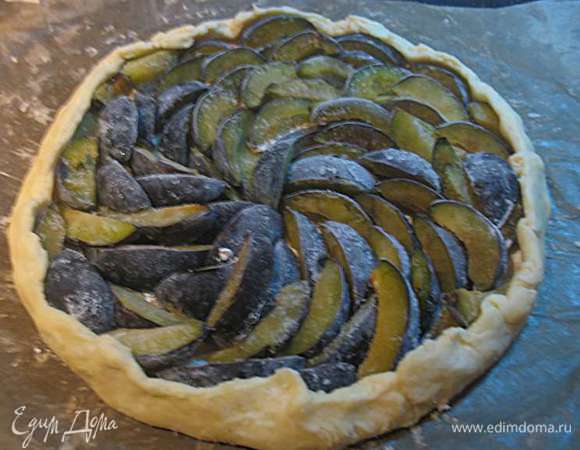 На тесто выложить сливу внахлест друг к другу, край оставить свободным.  Сформировать аккуратно бортик, вокруг сливы. 