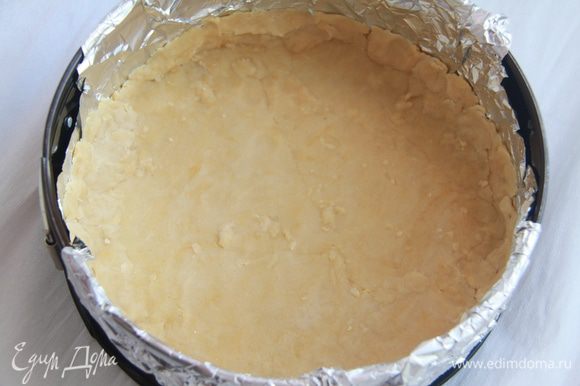 Из ингредиентов для основы приготовить тесто. Раскатать тесто в пласт диаметром на 1см больше формы, в которой будете выпекать пирог. Форму выстелить фольгой или бумагой для выпечки, выложить тесто, прижать ко дну формы, сформировать бортик высотой 1см.
